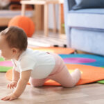 Baby demonstrating gross motor skills by crawling